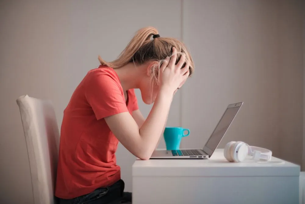 A frustrated girl trying to use a non accessible online service on her laptop.
